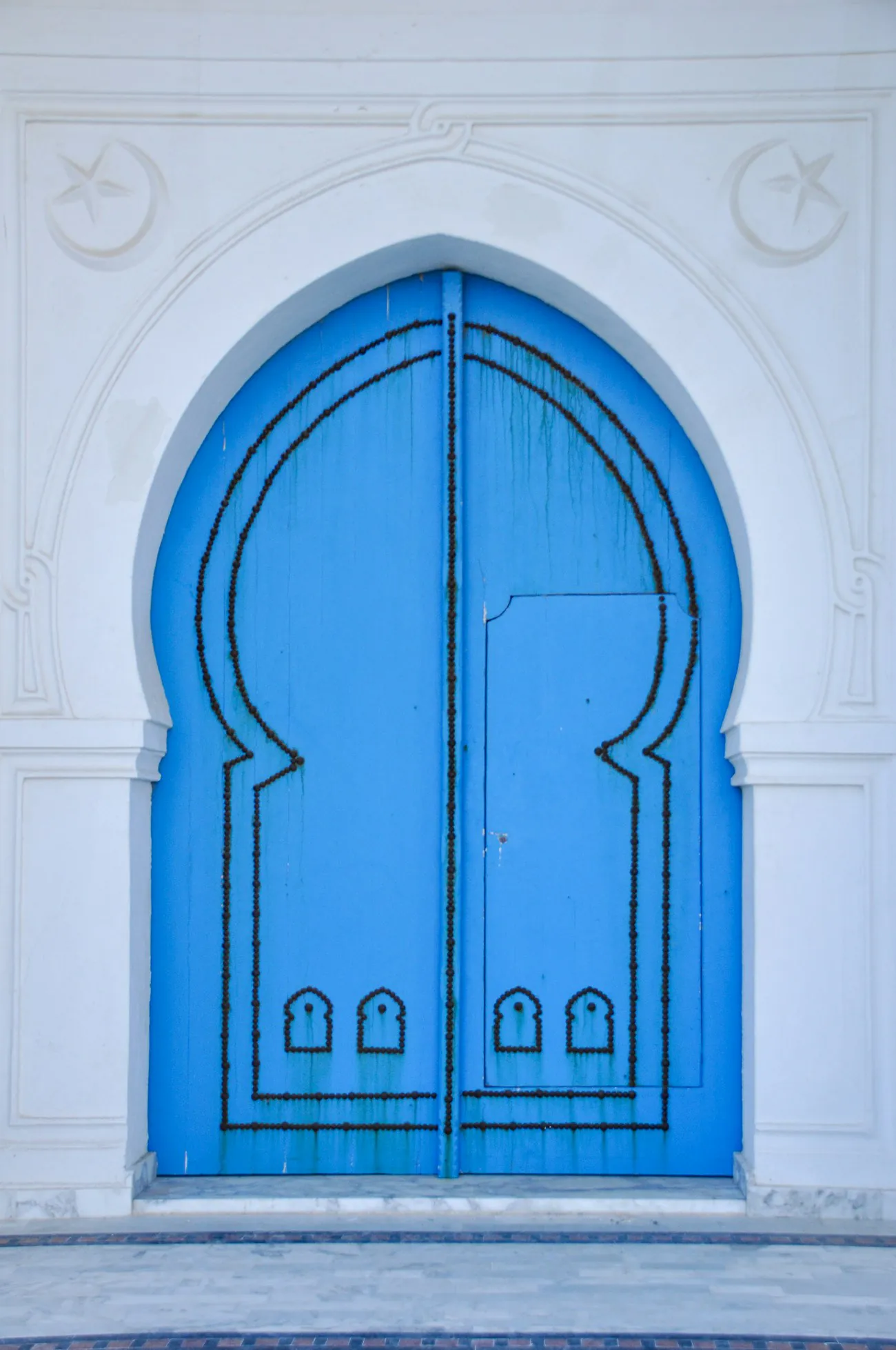 A blue arched door set in a white wall in Sidi Bou Said